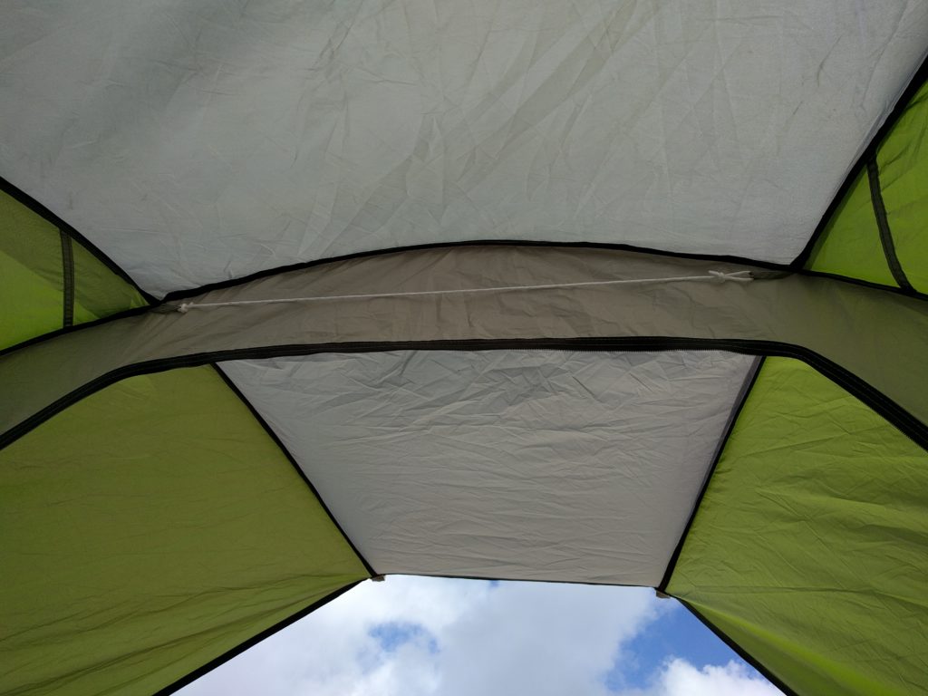 A view looking skyward from within a beach tent. The sky is mostly obscured by the beach tent's ceiling.