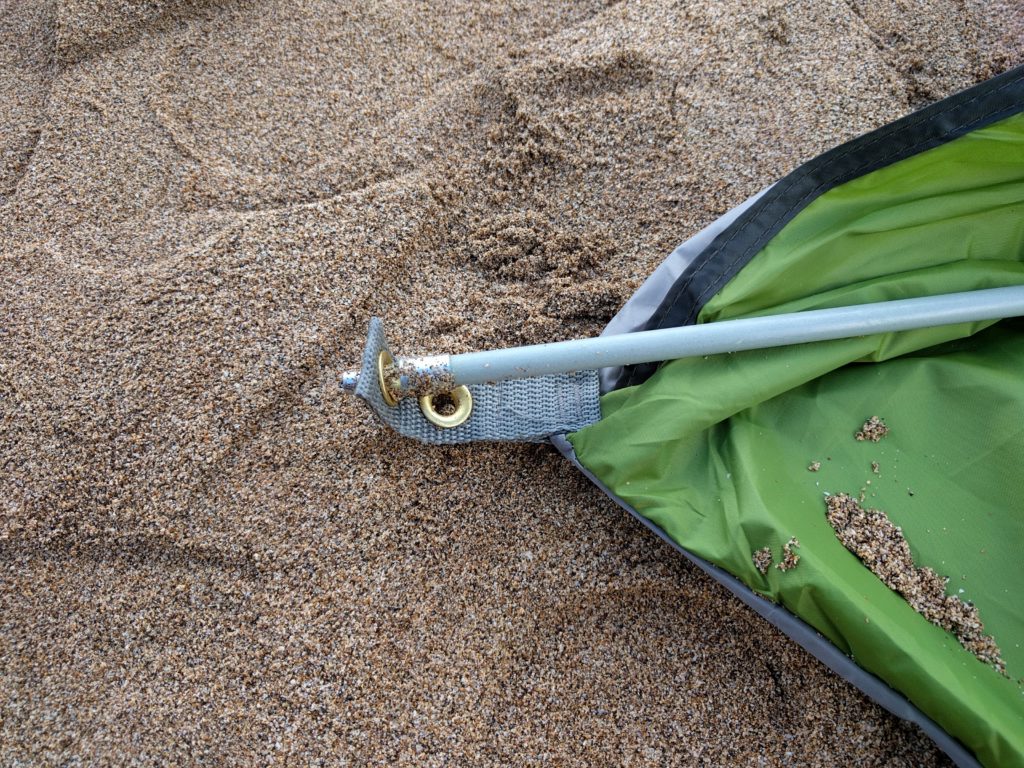An eyelet with a tent pole inserted into it, at the corner of a beach tent.