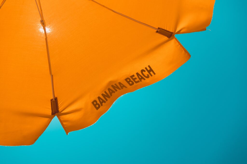 A bright orange beach umbrella, blocking the sunlight above.