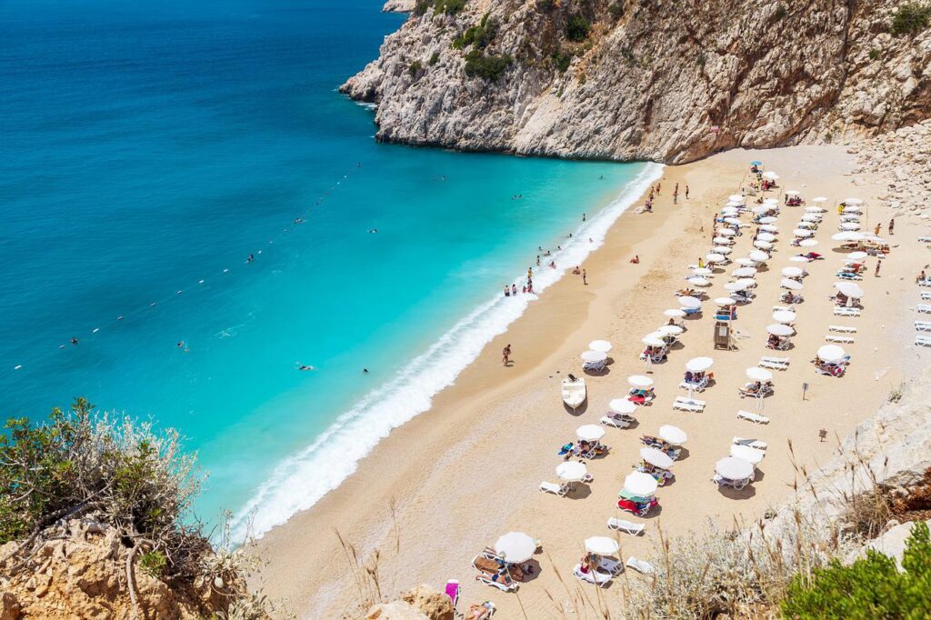 A beautiful beach front, rocks on either side, with beach umbrellas set up.